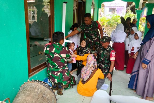 Danramil beserta Babinsa membantu kader dan bidan desa melaksanakan Posyandu Balita