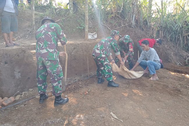 Anggota TNI bersama masyarakat melaksanakan gotong royong
